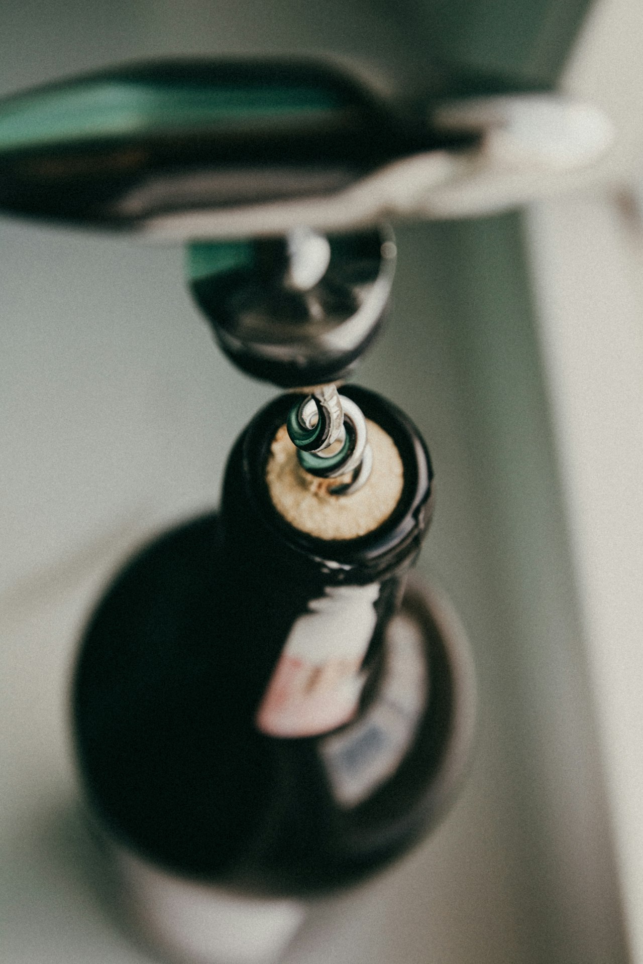 A gift-wrapped bottle of wine beside two glasses, a decanter, and a corkscrew on a wooden table