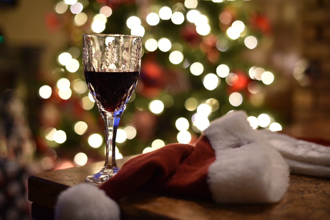 A bottle of wine in a simple gift bag with a handwritten note tag and a glass of red wine
