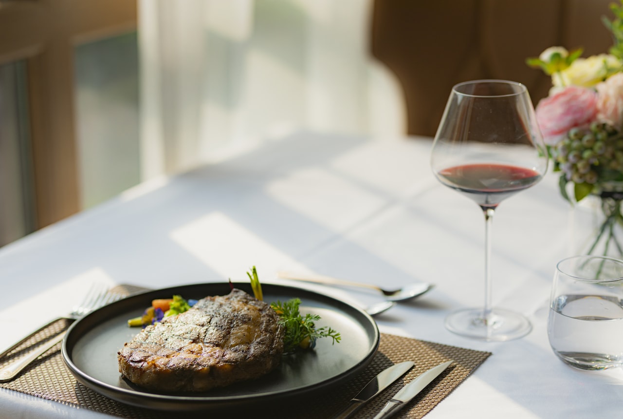 Seared steak with a glass of bold red wine plated for a romantic at-home dinner