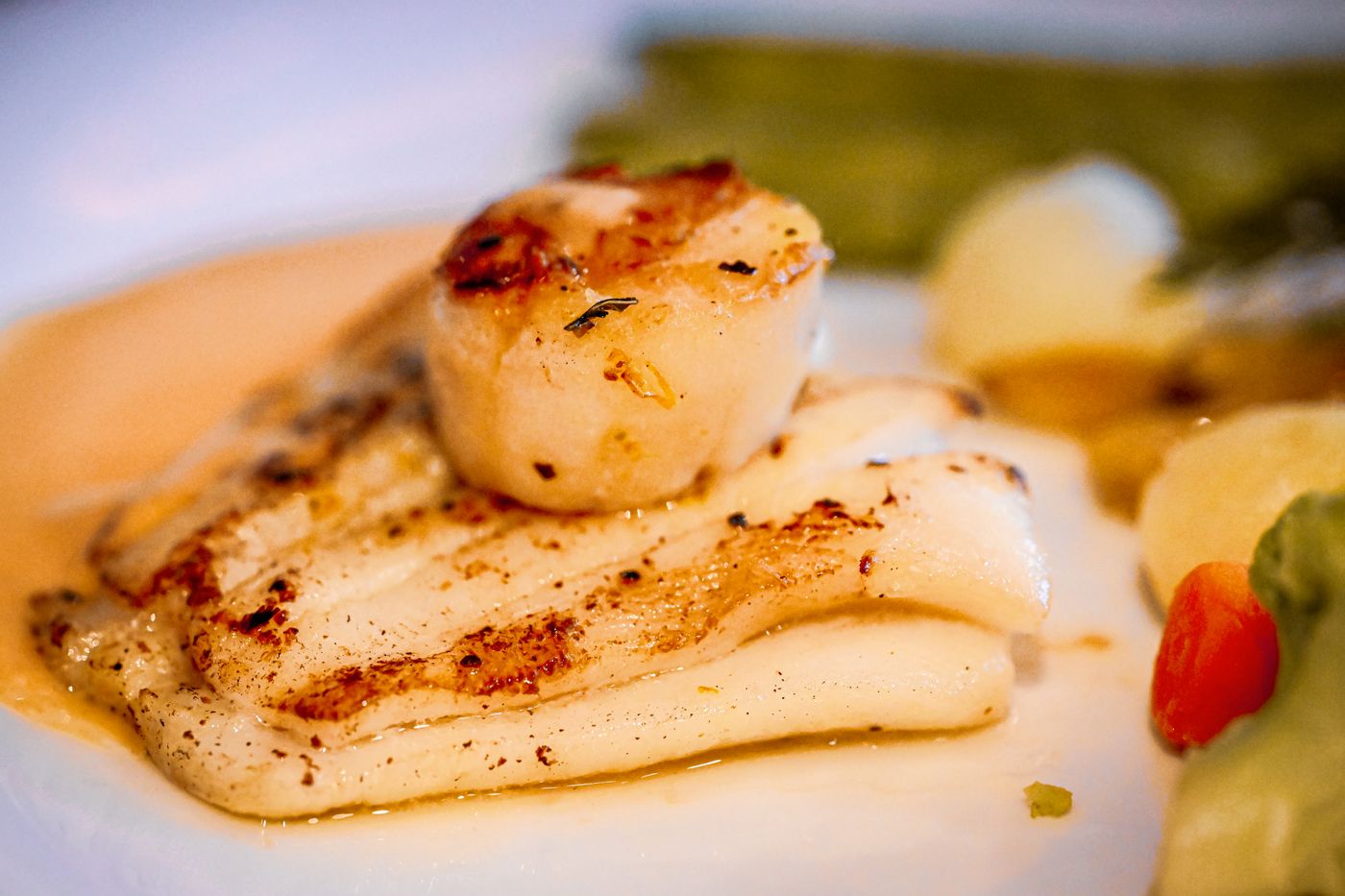 Pan-seared scallops with a golden crust plated beside a glass of crisp white wine