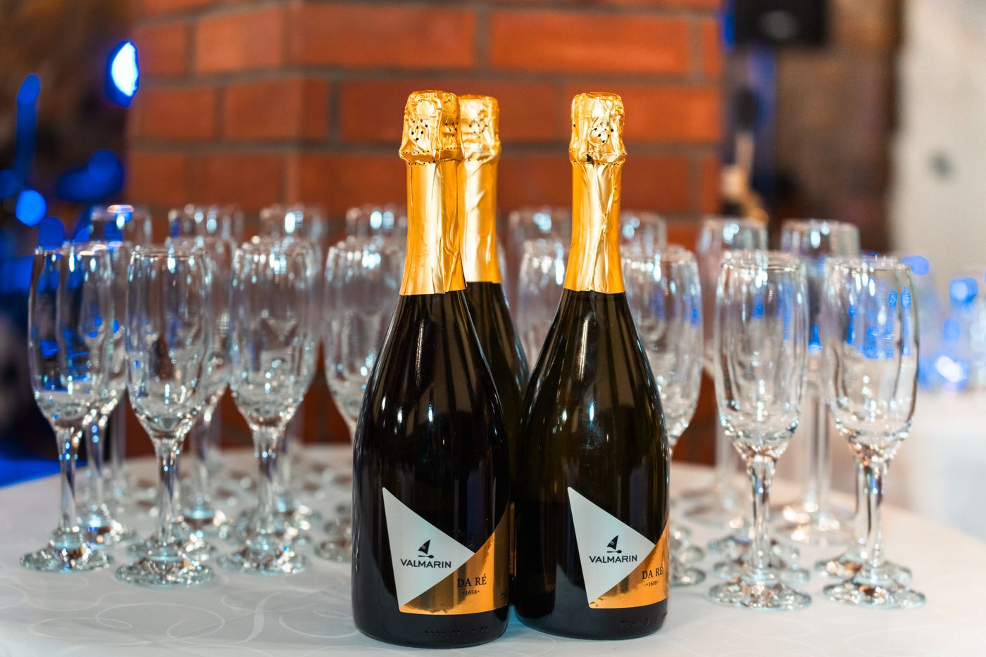 A table set for a party with rows of red and white wine bottles and stemware ready for fifty guests