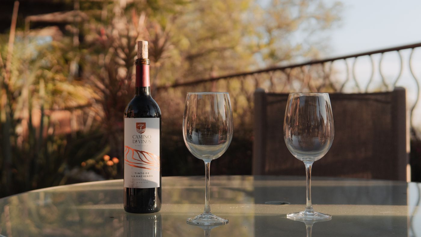 A 750 ml bottle of wine with poured five-ounce glasses on a table