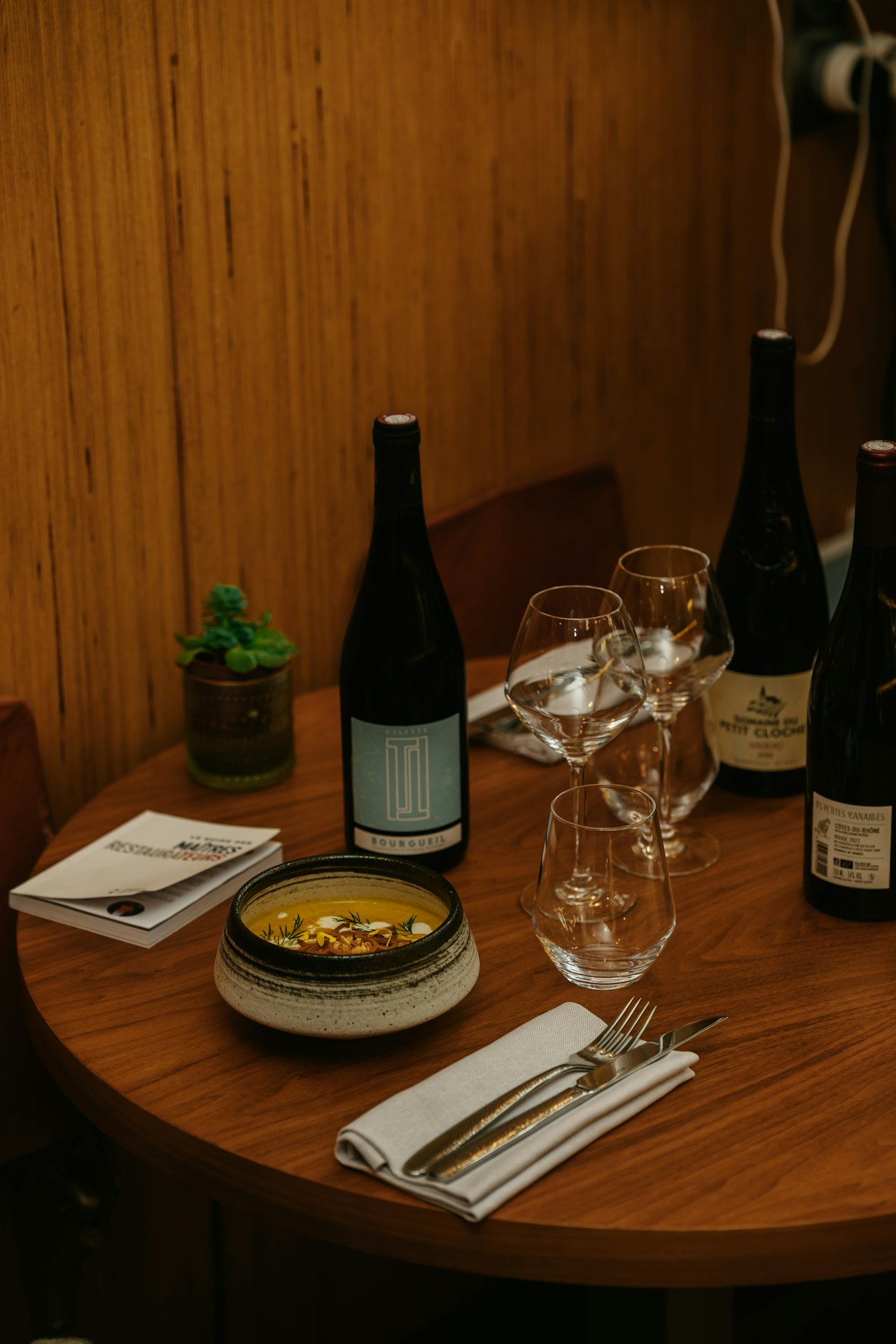 Several open bottles of red and white wine lined up on a party bar with rows of empty wine glasses ready to pour