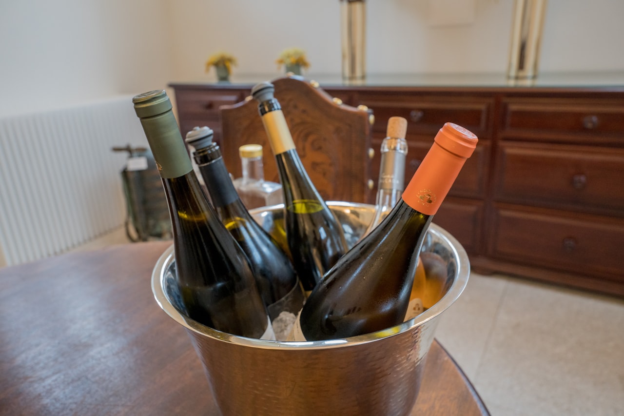 An assortment of red, white, and sparkling wine bottles chilling together in an ice bucket at an outdoor party