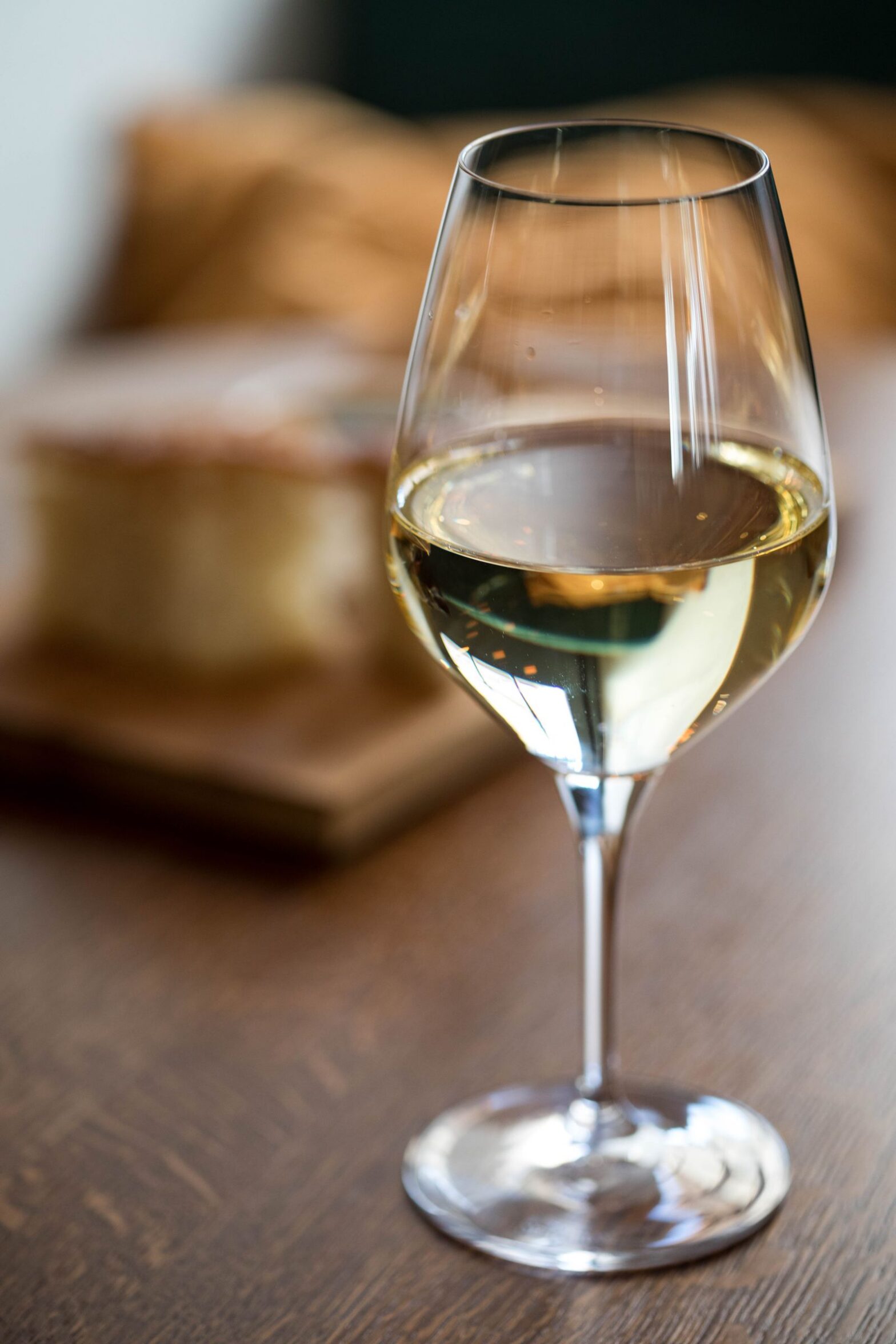 A goblet of white wine on a wooden table set for dinner, showing Pinot Grigio as a food wine