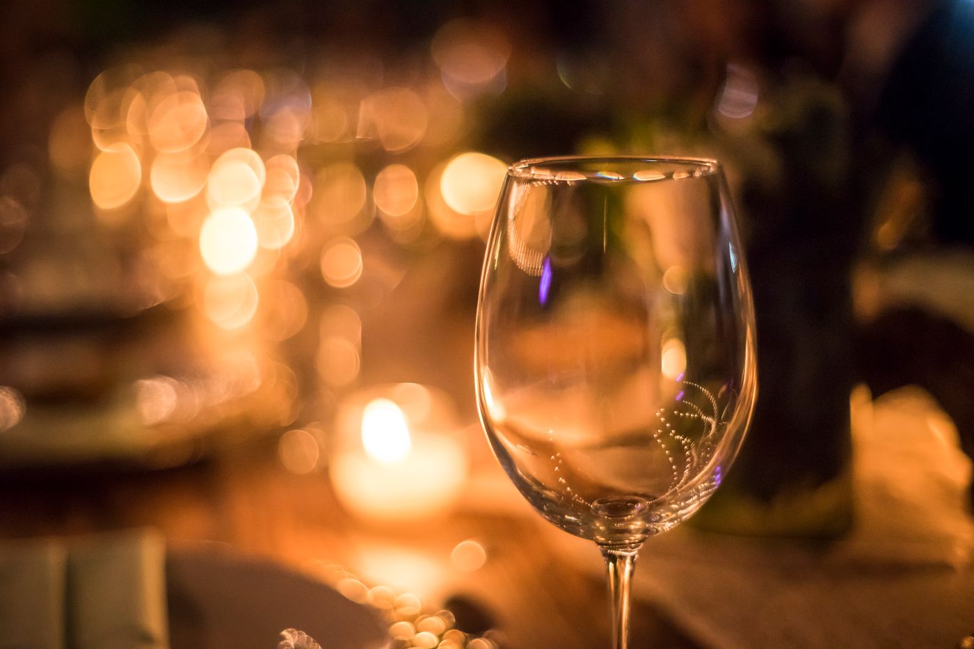 Candlelit romantic dinner table for two set with wine glasses and a single lit candle