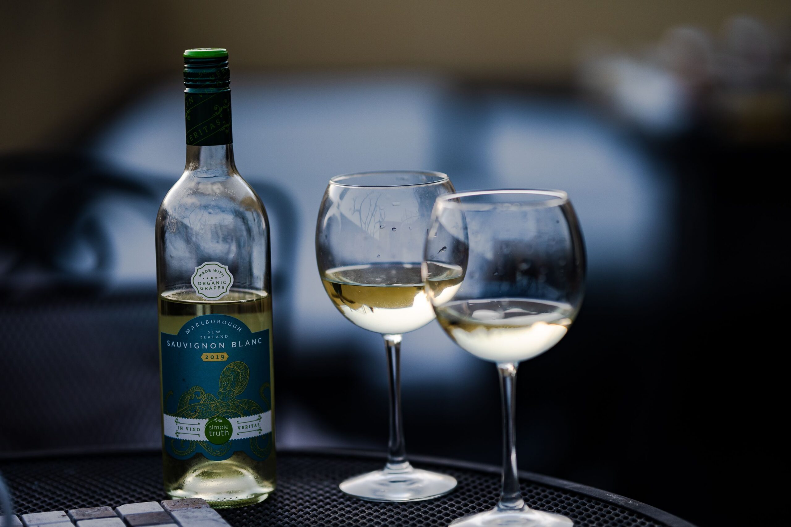 A bottle of Sauvignon Blanc beside two glasses of chilled white wine