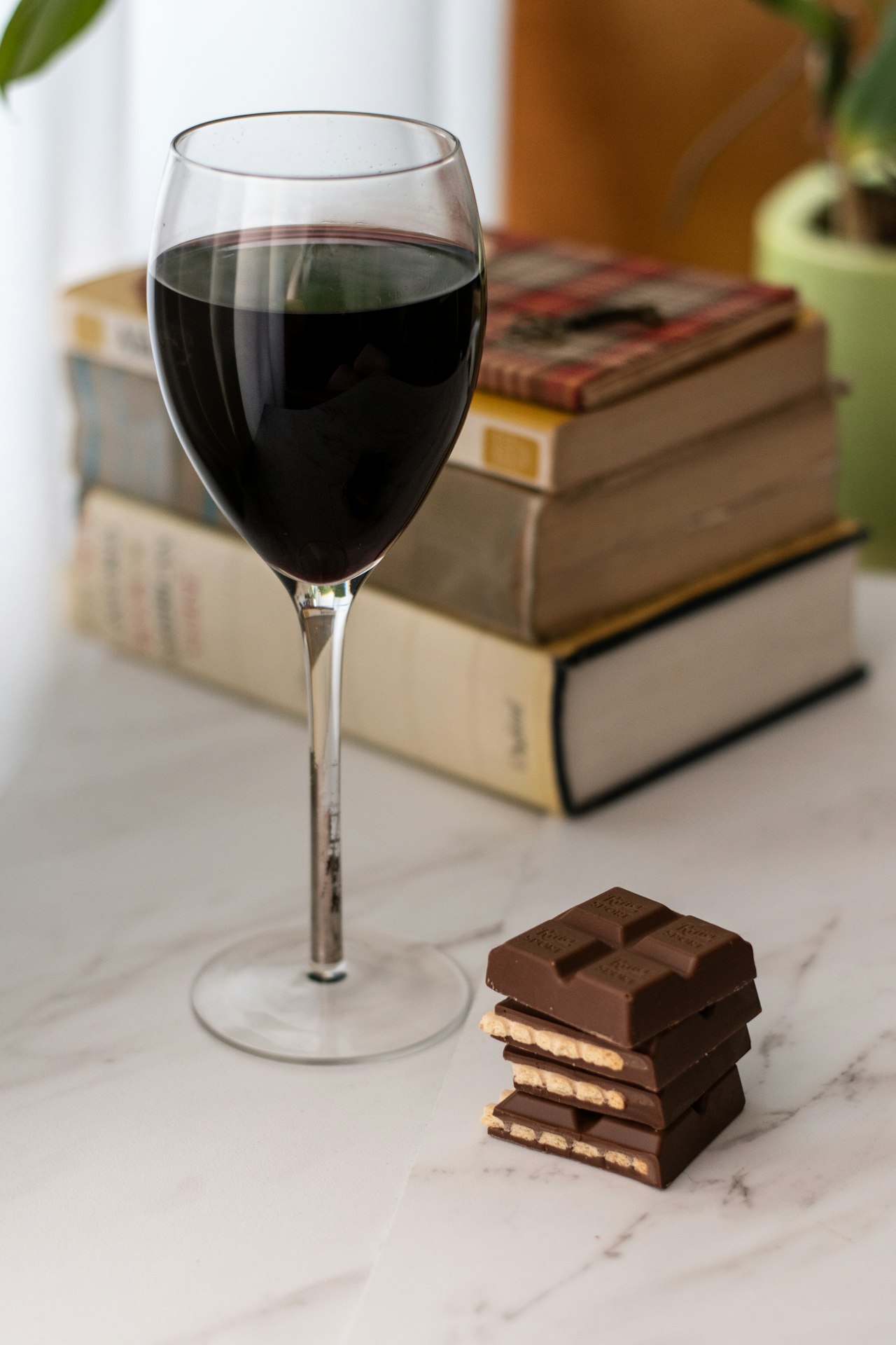 A glass of dark red wine beside squares of dark chocolate