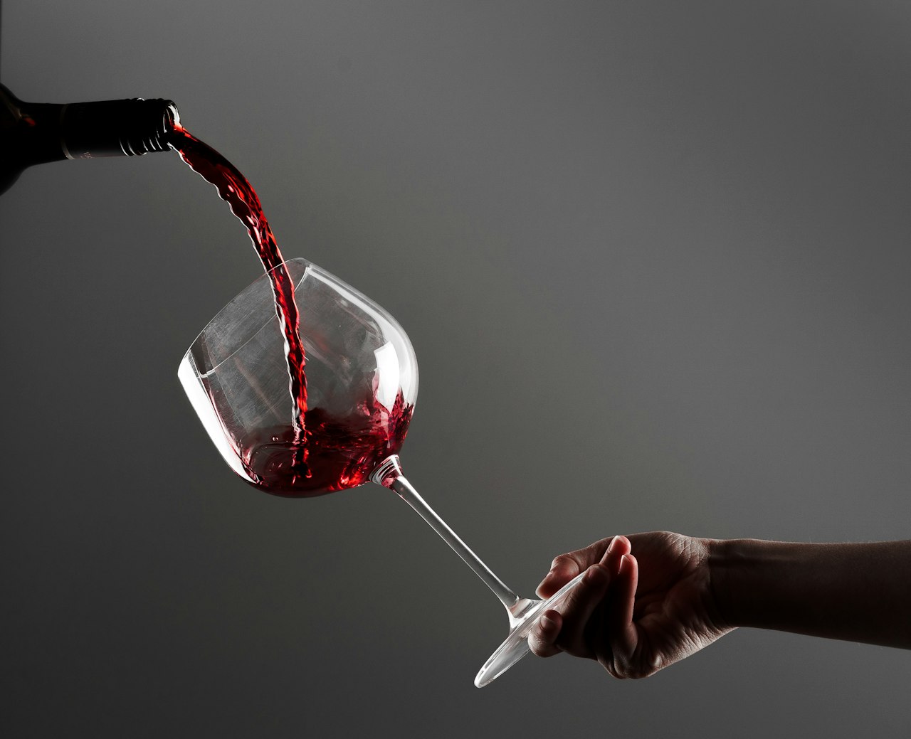 Dark red wine being poured into a tilted glass