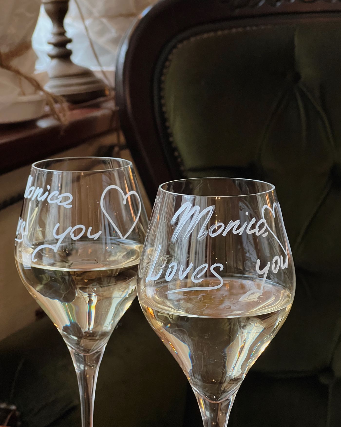An engraved wine bottle beside two etched wine glasses arranged as a wedding gift on a wooden table