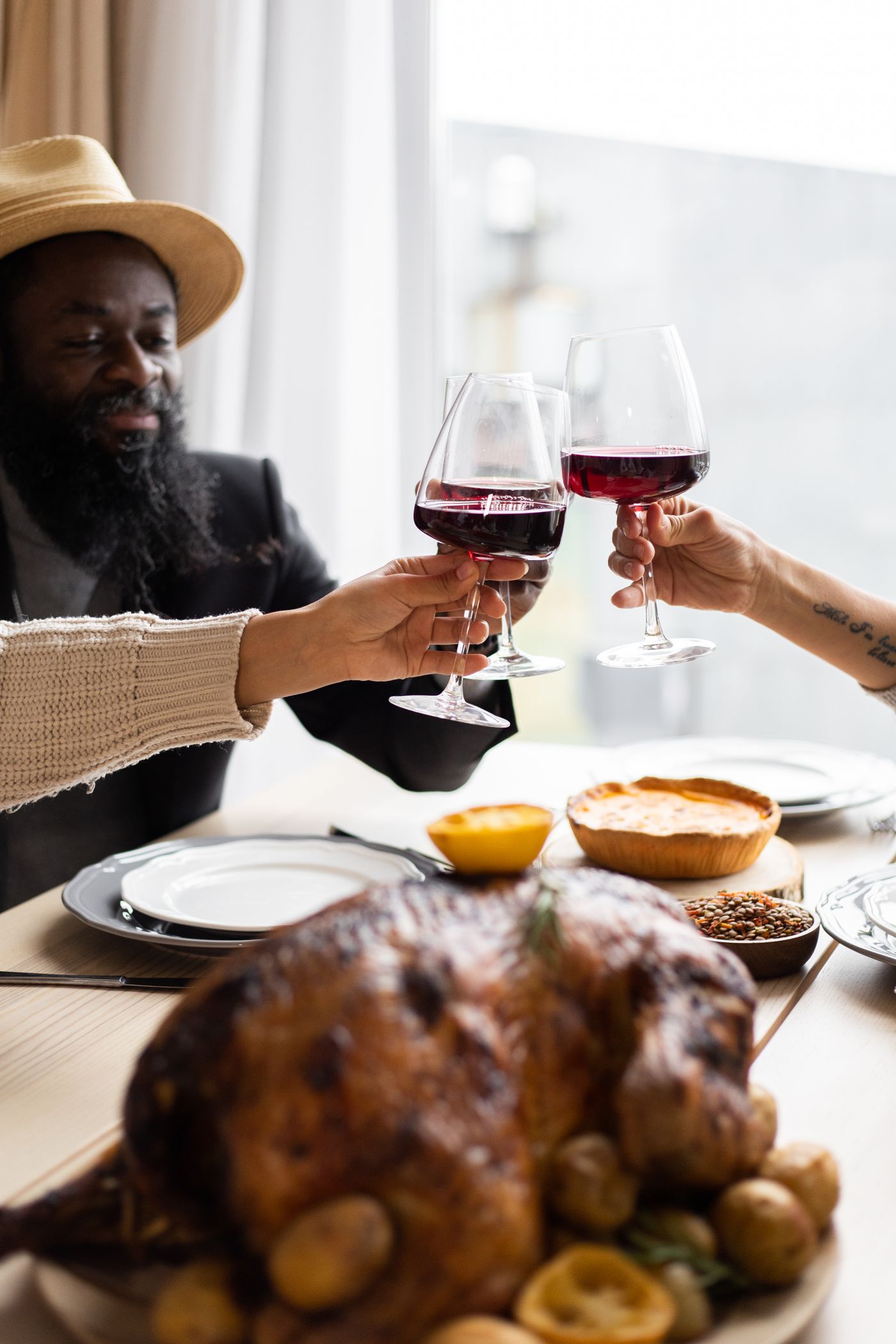 Roast turkey on a Thanksgiving table surrounded by side dishes and glasses of red and white wine