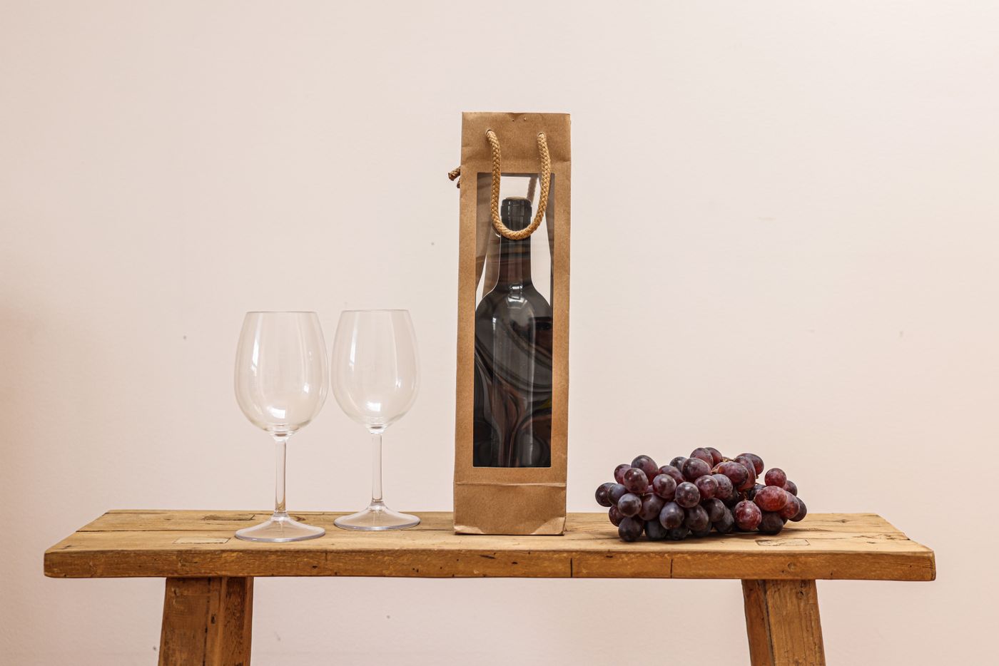 A bottle of wine in a gift bag with a handwritten gift tag on a host's entry table