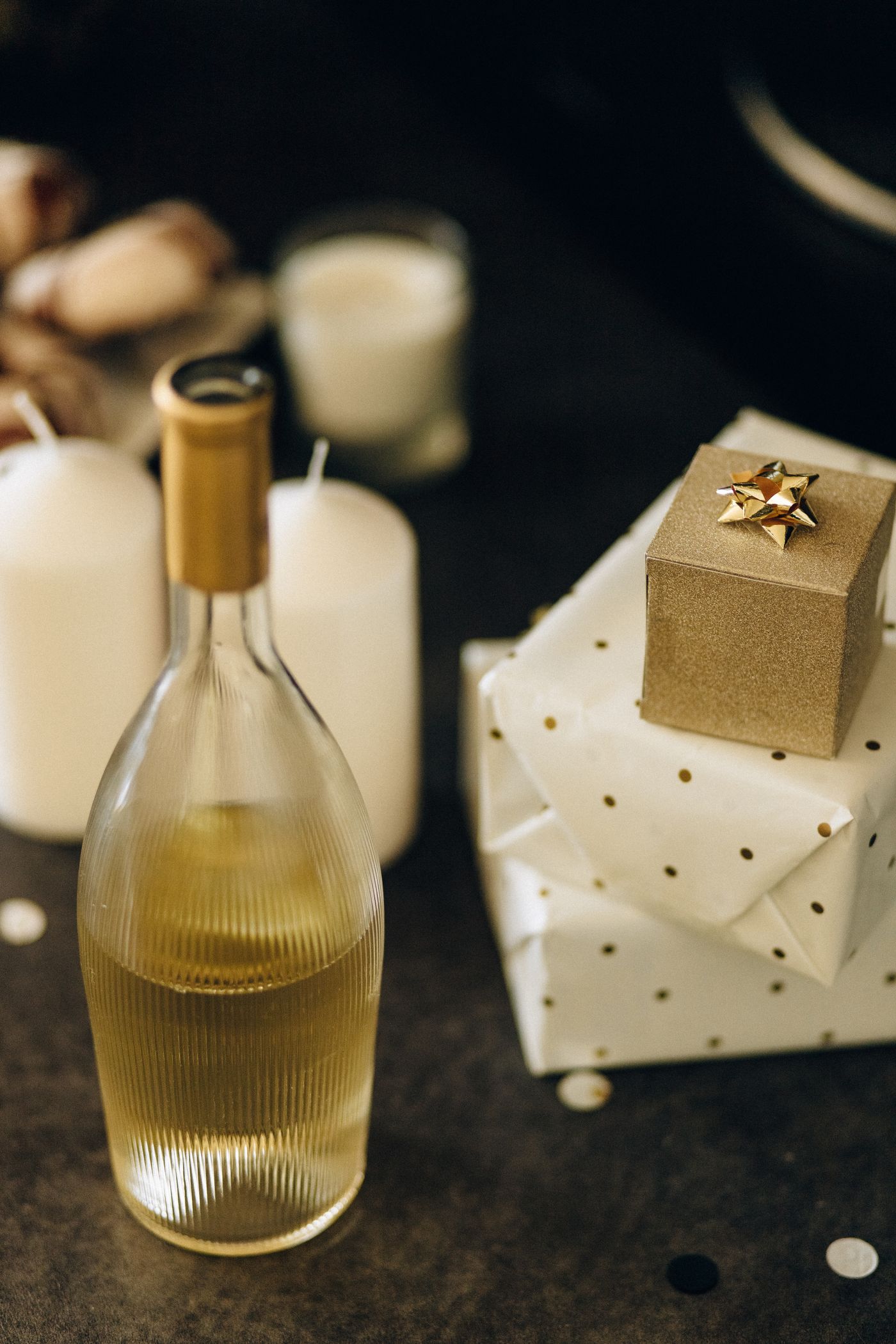 A gift-wrapped bottle of wine beside a wine aerator, a stopper, and two glasses on a wooden table